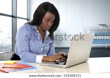 young attractive and efficient black ethnicity woman sitting at computer laptop desk typing concentrated working at modern business district office in business career and success concept