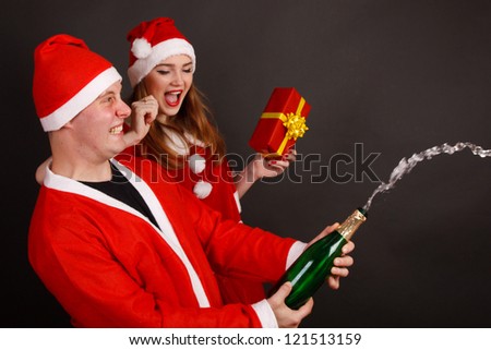 Happy traditional Santa Claus and mrs. Santa opens the champagne