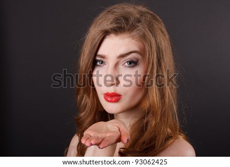 sexy young woman blowing a kiss on a black background