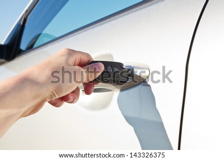 Male hand with key opening car door outdoors