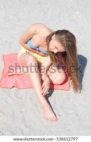 Young girl relaxing on the beach, and checks whether shaved legs