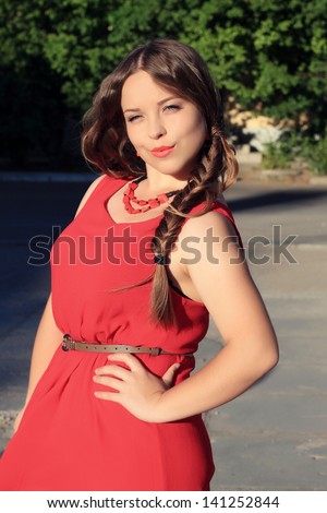 portrait of a beautiful long-haired plump woman in a red dress. outdoors