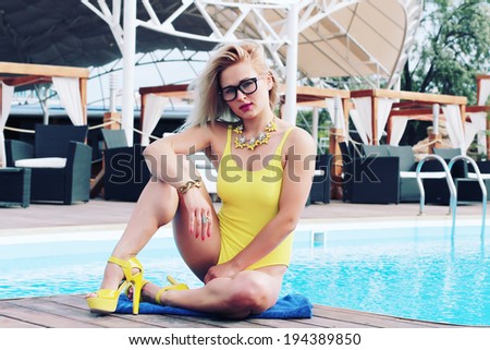 Fashion photo of sexy blonde posing by the pool. Outdoor shot. Photo toned style Instagram filters