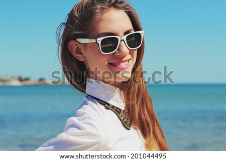 Happy young girl walking on the beach in the summer. Hipster glasses. Geek style. Outdoors. Photo toned style instagram filters