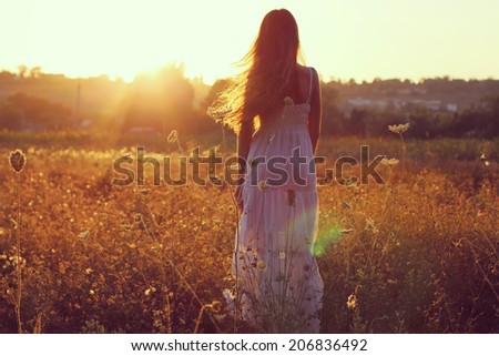 Pretty young woman in field at sunset. Photo toned style Instagram filters