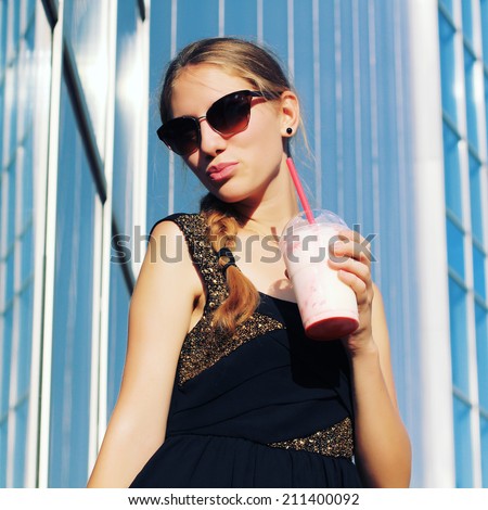 Woman hipster with glasses drinking strawberry smoothie making funny face with a retro vintage instagram filter