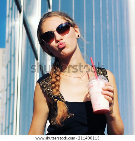 Woman hipster with glasses drinking strawberry smoothie making funny face with a retro vintage instagram filter