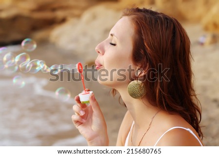 Girl blowing soap bubbles on the sea shore with Instagram filters.