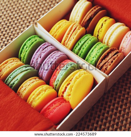 Sweet and colorful macaroons in the cardboard box with the top view. Multicolored delicious French pastries in a row with a retro vintage instagram filter.