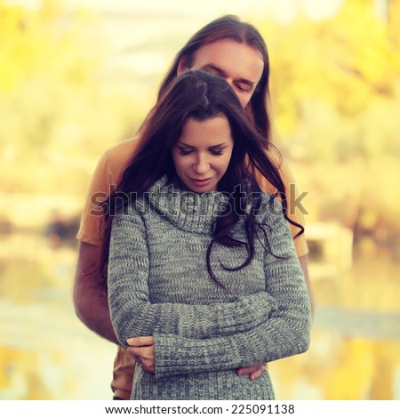 Sensual outdoor portrait of stylish fashion couple embracing in autumn field. Photo toned style Instagram filters.
