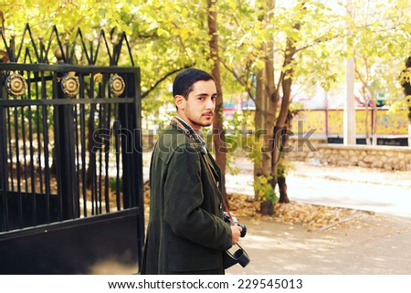 Outdoor autumn portrait of young fashion handsome hipster man with vintage camera. Photo toned style instagram filters