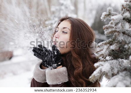 Beautiful young fashionable woman in black hat playing with snow outdoor winter lifestyle happiness emotions nature on background. People, holidays, fashion and magic concept