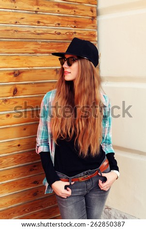 Portrait of beautiful cool young woman gesturing in hat and sunglasses over grunge wall. Swag girl. Sexy fashion portrait toned style Instagram filters.