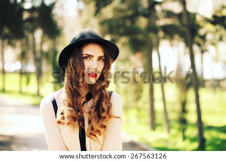 High fashion look. Glamor stylish beautiful young woman model with red lips in hipster cloth and vintage black hat. Outdoor, lifestyle