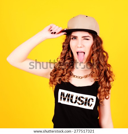 Indoor portrait of young pretty blonde hipster girl, wearing swag style clothes and hat. Yellow background.