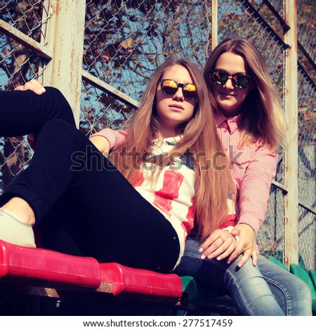 Close up fashion portrait of two sisters having fun together, wearing bright stylish mirrored sunglasses, best fiend enjoy amazing time together.