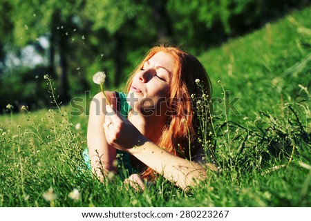 a red head girl blowing on a dandelion done with a vintage retro instagram filter