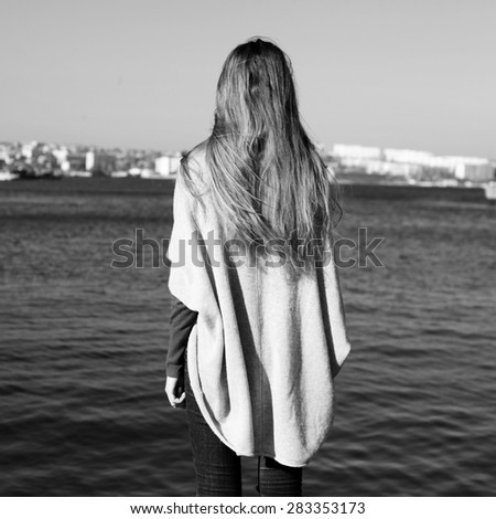 Beautiful girl hippie standing back and looking at the sea.