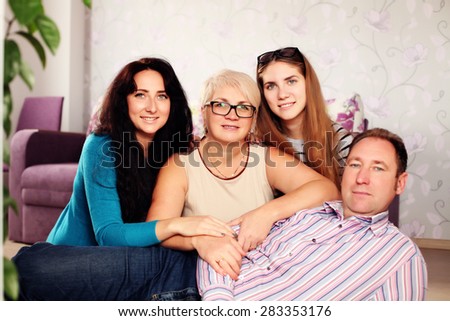 Happy family looking at the camera. Family at home relaxing on carpet. Indoors, lifestyle