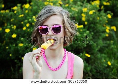 Young sexy blonde girl eating orange ice cream in summer hot weather in mirror sunglasses have fun and good mood and smiling