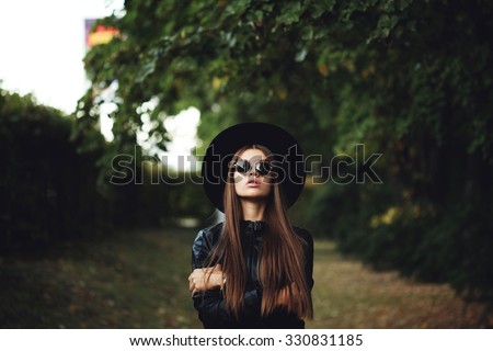 Street fashion concept - closeup portrait of a pretty girl. Wearing hat and leather jacket, round sunglasses. Autumn woman. Artsy bohemian rock style. Fall fashion. Toned style instagram filters