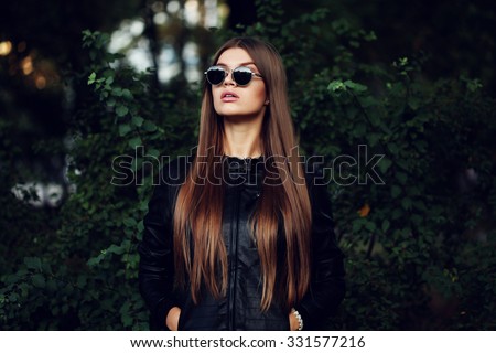 Street fashion concept - closeup portrait of a pretty girl. Wearing leather jacket, round sunglasses. Autumn woman. Artsy bohemian rock style. Fall fashion. Toned style instagram filters