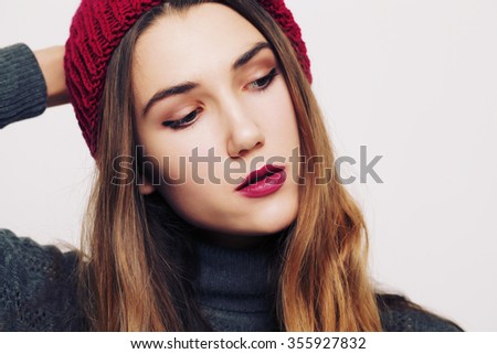 beauty portrait of a young beautiful girl with long ombre straight hair wearing marsala color warm hat. Magnificent hair. Lips care