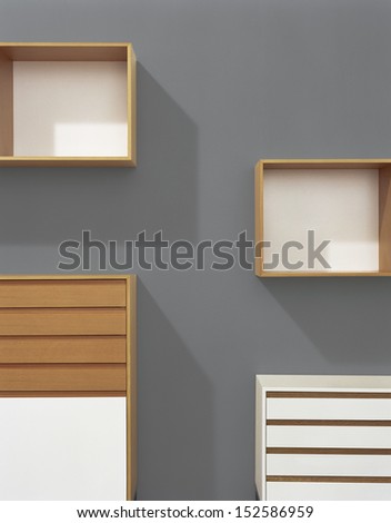 Part of cupboards and shelves on a grey wall.