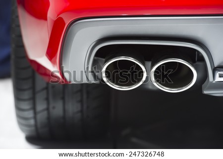 Chrome exhaust pipe of red powerful sport car bumper
