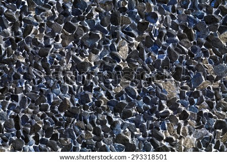 Granite and stone gravel, crushed rough small nature construction material with sharp edges on white glowing liquid background, mystic abstraction of black, dark blue and grey colors, texture