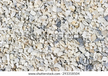 Granite and stone gravel, crushed rough small nature construction material with sharp edges at sunny day, white, beige and grey colors background, abstraction, texture