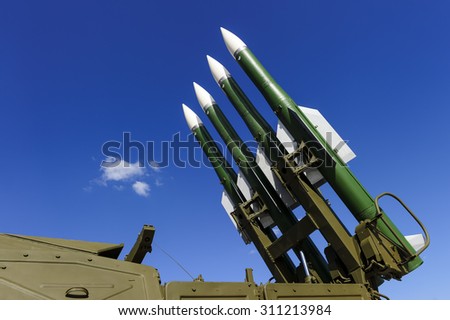 Ballistic rocket launcher with four cruise missiles on powerful mobile transportation with blue sky and white clouds on background, antiaircraft forces, military industry