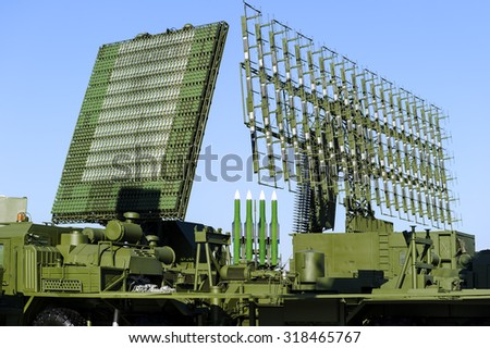 Air defense radars of military mobile antiaircraft systems in green color and ballistic rocket launcher with four cruise missiles in centre of frame, modern army industry
