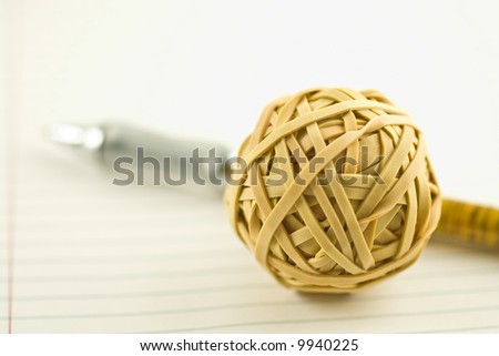 rubber band ball and pen on notebook paper with shallow depth of field