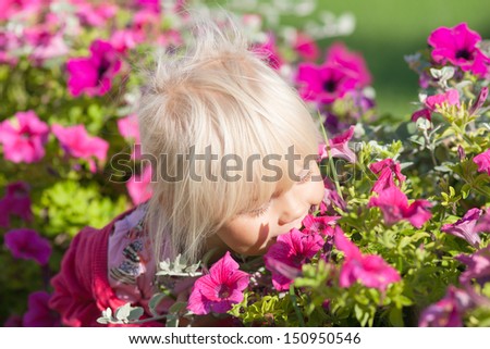 Cute little girl smells flowers