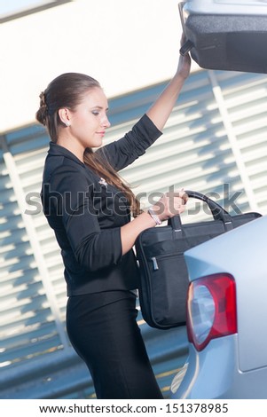 Businesswoman takes her laptop bag out from the car