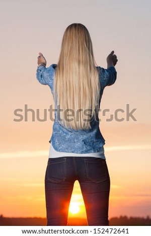 Blonde woman lifts hands up to the sun