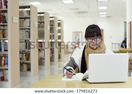 Chinese girl reading using a computer in the library