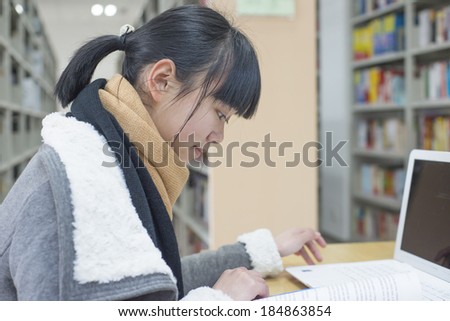 Chinese girl reading using a computer in the library