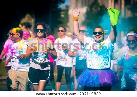 MORRISTOWN, NJ, USA - JUNE 6, 2014: Happy woman runs the Color Vibe 5K race. Color Vibe is a fun un-timed event with no winners or prizes where runners are showered with colored powder along the run.
