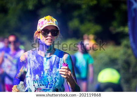 MORRISTOWN, NJ, USA - JUNE 6, 2014: Young woman runs the Color Vibe 5K race. Color Vibe is a fun un-timed event with no winners or prizes where runners are showered with colored powder along the run.