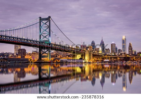 Ben Franklin bridge and Philadelphia skyline reflected in the Delaware river under a purple twilight