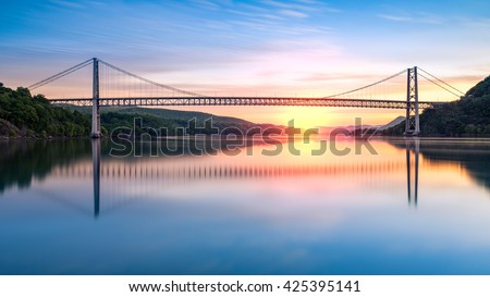 Bear Mountain Bridge at sunrise (long exposure). Bear Mountain Bridge is a toll suspension bridge in New York State, carrying U.S. Highways 202 and 6 across the Hudson River