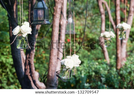 White roses in a glass vase hung in a wedding party