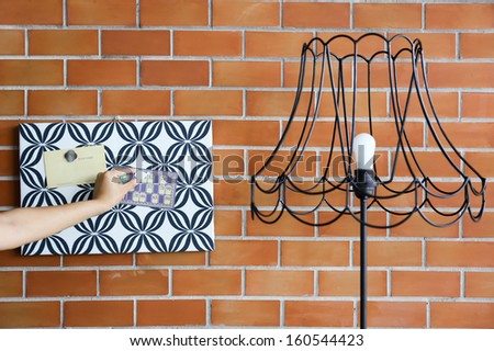 Hands putting magnet memo on pattern cardboard with vintage lamp and brick wall background