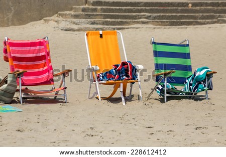 three colorful chairs on the sand, near the beach