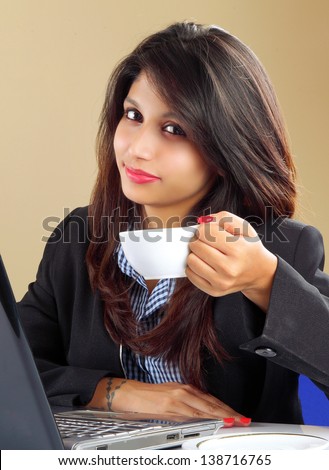 Portrait of a smiling Indian business woman working on her desk along with tea cup.