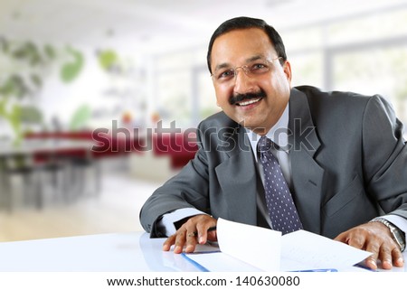 Image of young Indian man looking at camera with his writing pad near by