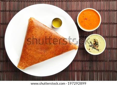 Popular south indian breakfast ghee roast  dosa in golden brown color with 3 types of side dishes.