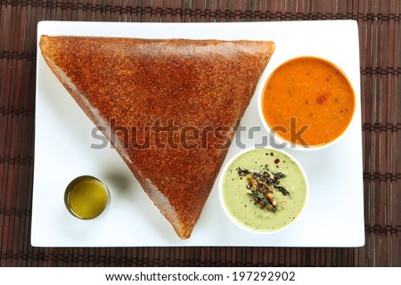 Popular south indian breakfast masala dosa in golden brown color with 3 types of side dishes.